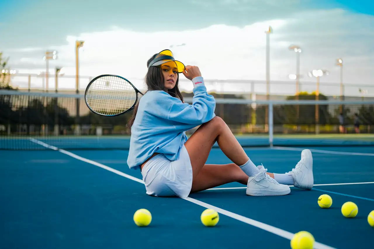 Tennisspeelster met racket op een hardcourtbaan, tussen verspreide ballen