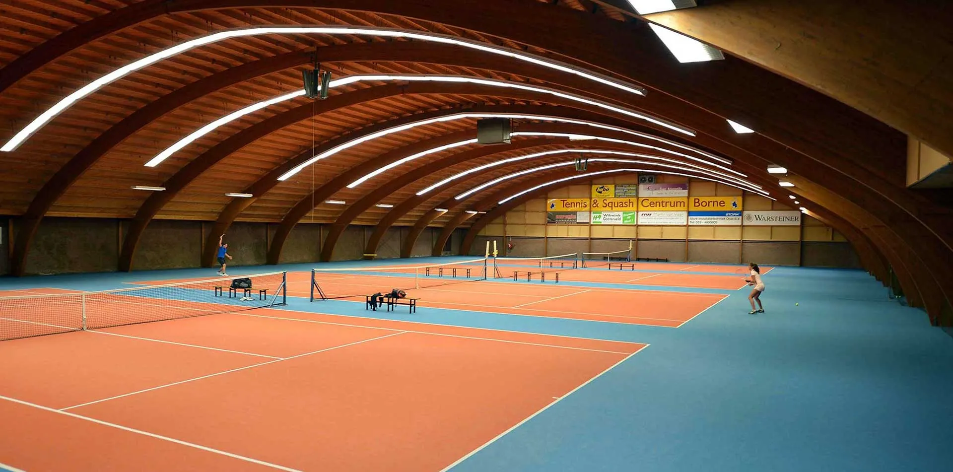 Indoor tennisbanen onder het houten tongewelf in Borne